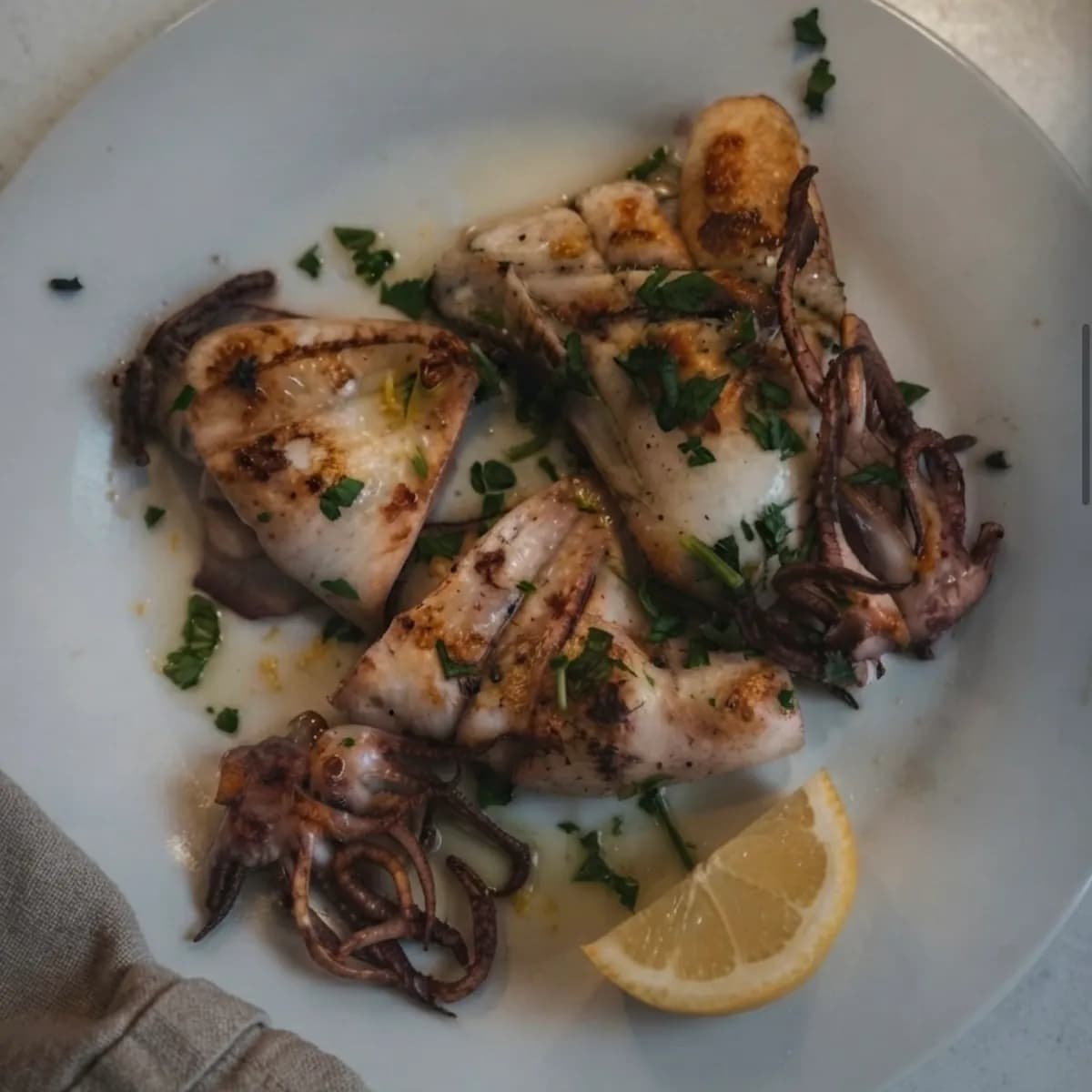 Calamaro grigliato con prezzemolo e uno spicchio di limone
